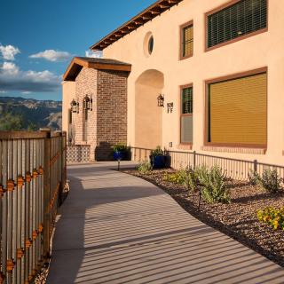 A sunny view of a modern house with a landscaped pathway in a desert setting.