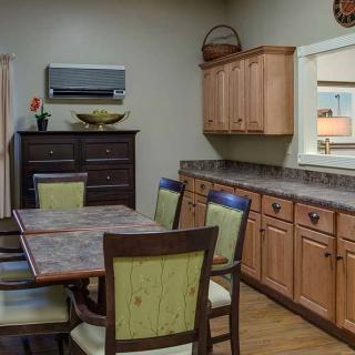 A cozy kitchen and dining area featuring a wooden table, chairs, cabinets, and a countertop.