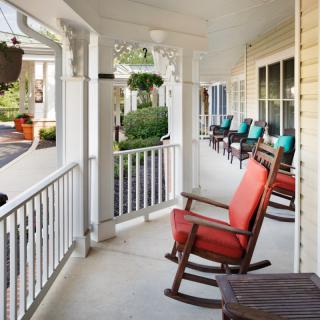 A cozy porch featuring several rocking chairs, perfect for relaxation and enjoying the outdoor view.