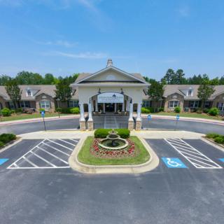 A symmetrical entrance to a large building with landscaped surroundings and a parking lot.
