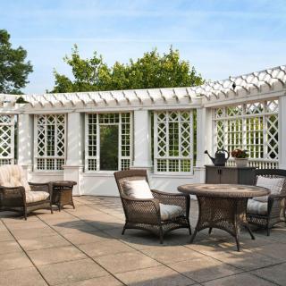 A stylish patio with wicker furniture and a white pergola, ideal for outdoor relaxation.