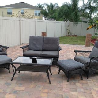 A set of outdoor patio furniture consisting of sofas, chairs, and a table in a backyard setting.