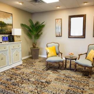 A cozy waiting room featuring elegant furniture, a decorative plant, and tasteful artwork.
