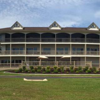 A multi-story residential building with balconies and a green lawn under a cloudy sky.