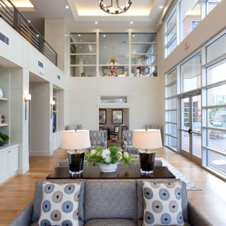 A modern lobby area with tall ceilings, large windows, and stylish furniture.