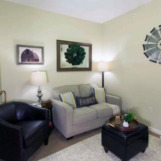 A cozy living room featuring a cushy sofa, armchair, and decorative elements like wall art and lamps.