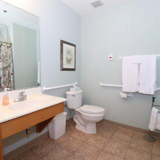 A clean, well-lit bathroom with a toilet, sink, and mirror.