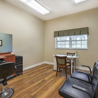 A neatly arranged salon room with chairs, a mirror, and a window.