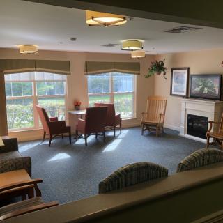 A cozy living room with chairs and a fireplace, featuring large windows and ample natural light.