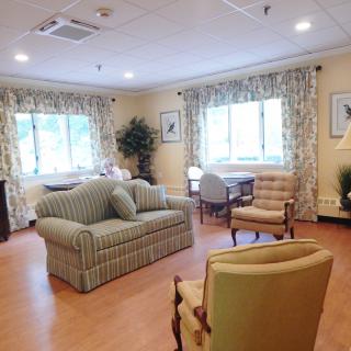A cozy living room with a sofa, chairs, and large windows.