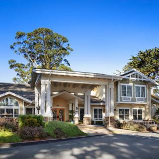 A picturesque building with a welcoming entrance, surrounded by lush greenery and clear blue skies.