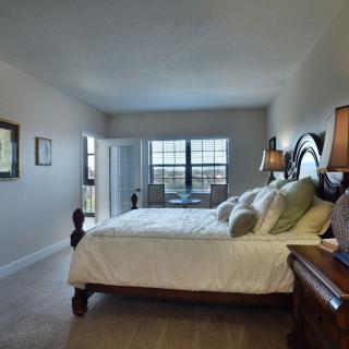 A spacious and elegantly decorated bedroom with a comfortable bed, large windows, and stylish furnishings.