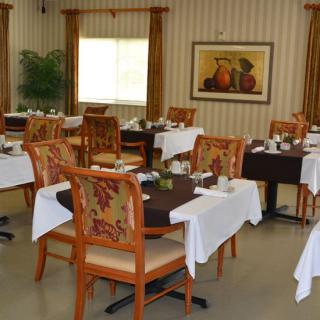 A tastefully decorated dining room with multiple tables and chairs, set for dining.