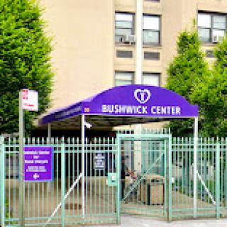 The entrance of the Bushwick Center, featuring its distinct purple awning and gated access.