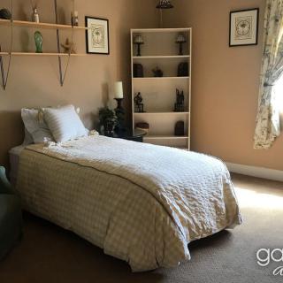 A cozy bedroom with a single bed, shelves, and decorative elements.