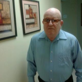A man standing in a hallway adorned with framed artwork.