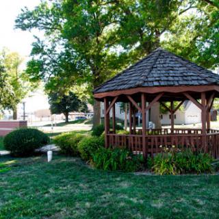A charming gazebo surrounded by lush greenery in a peaceful park setting.