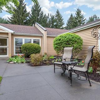 A cozy outdoor patio area with seating, surrounded by well-maintained landscaping and green bushes.