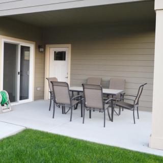 A covered patio area with outdoor furniture set in a backyard.