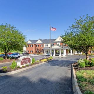 A well-maintained building entrance with a flagpole and surrounding greenery.