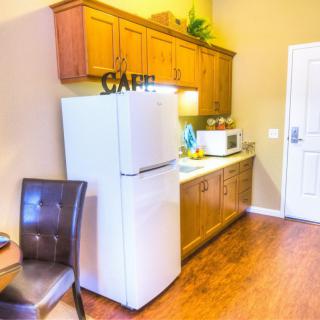 A compact kitchen area with a fridge, microwave, and wooden cabinets.