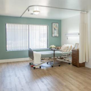 A serene and neatly arranged hospital patient room with natural light filtering through the windows.