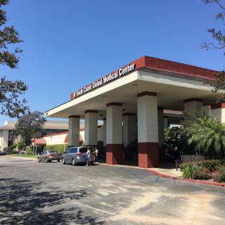 A healthcare facility entrance with a clear blue sky above.