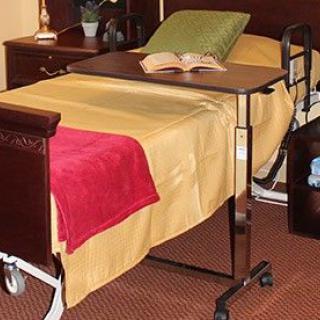 A hospital bed with an adjustable overbed table and a book placed on it.