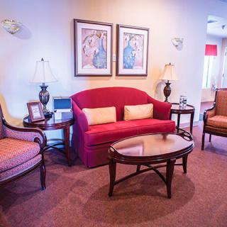 A cozy living room with a red sofa, matching chairs, and elegant decor.