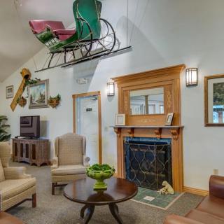 A cozy living room with vintage decor and a sleigh displayed above the fireplace.