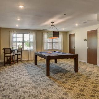 A spacious game room featuring a pool table and seating area with warm lighting.