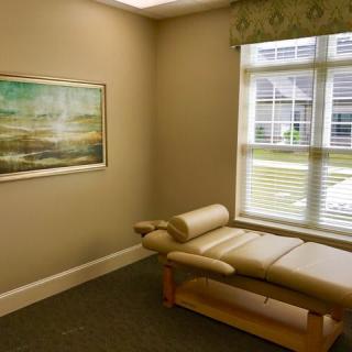 A serene therapy room with a massage table and a large window.