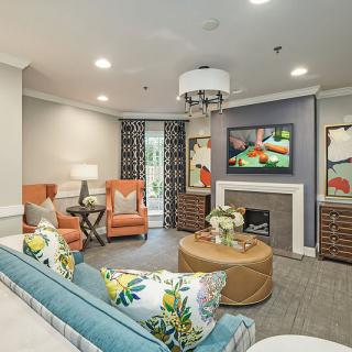 A modern living room with vibrant decor, featuring a sofa, chairs, and a fireplace.