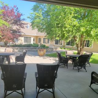 A serene outdoor seating area surrounded by lush greenery and sunlight.