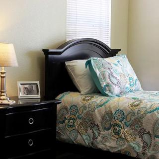 A cozy bedroom with a neatly made bed, nightstand, and lamp.