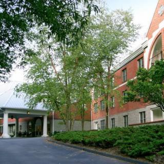 A brick building with trees lining its entrance.