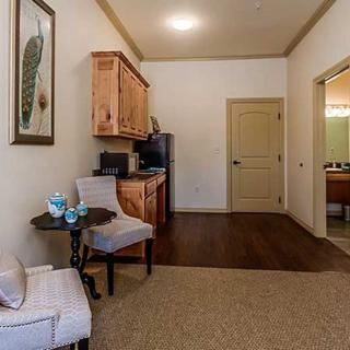A cozy living space with an armchair, table, and a kitchenette area.