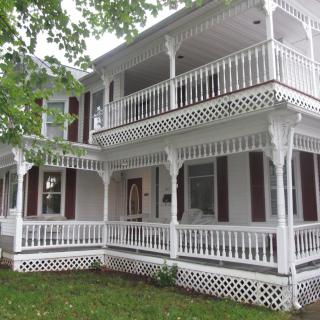 A white Victorian-style house with intricate balconies and a spacious porch.