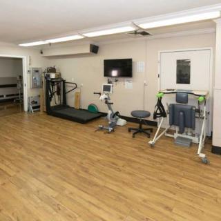 A small fitness room equipped with a treadmill, stationary bike, and other exercise machines.