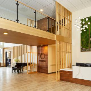 A modern lobby with a grand piano, wooden accents, and a stylish reception desk.