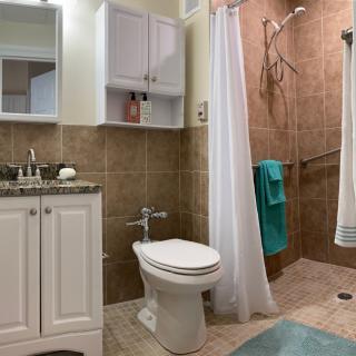 A modern bathroom with a toilet, sink, shower, and cabinet.