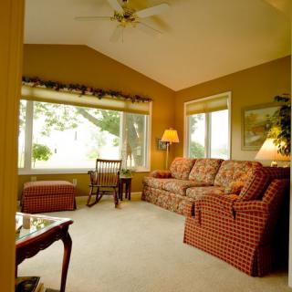 A cozy living room with patterned sofas, large windows, and warm lighting.