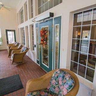 A cozy indoor patio area with floral chairs and decorative glass doors.