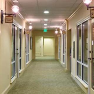 A well-lit hallway in an office building with glass doors on either side.