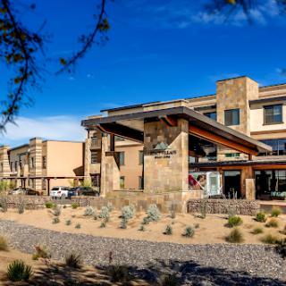 A modern hotel featuring a blend of stone and wood architecture set against a clear blue sky.
