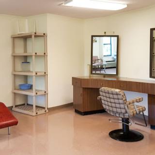 A minimalist hair salon interior featuring a stylish chair, a mirror, and a shelf.