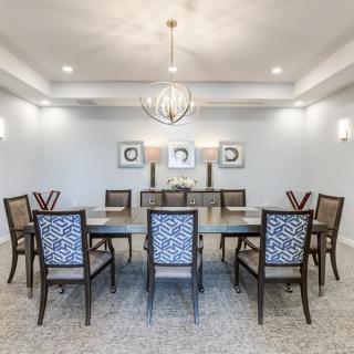 A spacious dining room with a large table and elegant chairs, complemented by a modern chandelier and wall art.