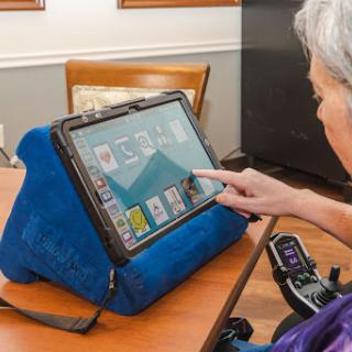 A senior individual using a tablet on a stand, highlighting the role of technology in enhancing accessibility and independence.