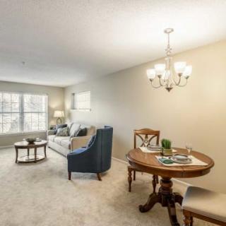 A cozy living room and dining area with a sofa, chairs, and a chandelier.