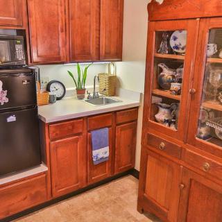 A cozy kitchen with wooden cabinets, a sink, and a glass-fronted hutch displaying dishes.